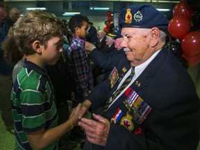 Second World War veteran Sheldon Lawr, shakes hands with a Grade 6 student from Davisville Public School after pinning a poppies on the boy at the launch of Toronto Royal Canadian Legion's annual TTC Poppy Campaign at North York Centre Station in Toronto, Ont. on Friday Oct. 27, 2017.