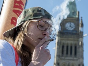 A woman smokes a joint during the annual 420 marijuana rally on Parliament hill on Wednesday, April 20, 2016 in Ottawa.
