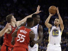 Golden State Warriors' Stephen Curry, right, shoots against Toronto Raptors' Jakob Poeltl, left, as Warriors' Draymond Green, second from right, blocks Raptors' Delon Wright (55) during the second half of an NBA basketball game Wednesday, Oct. 25, 2017, in Oakland, Calif. Warriors won, 117-112. (AP Photo/Ben Margot)