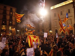 Pro-independence supporters release fireworks and wave "estelada" or pro independence flags gathered in the square outside the Palau Generalitat in Barcelona, Spain, after Catalonia's regional parliament passed a motion with which they say they are establishing an independent Catalan Republic, Friday, Oct. 27, 2017.