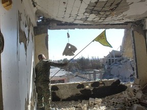 In this picture taken on Monday Oct. 16, 2017 and provided by The Syrian Democratic Forces (SDF), a U.S.-backed Syrian Kurdish forces outlet that is consistent with independent AP reporting, shows a Syrian Democratic Forces (SDF) fighter, waves his Kurdish party flag at the front line where they battle against the Islamic State militants, in Raqqa, Syria. (Syrian Democratic Forces via AP)