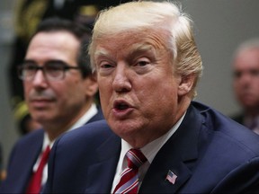 U.S. President Donald Trump speaks to business leaders as Secretary of the Treasury Steven Mnuchin (left) looks on during a Roosevelt Room event October 31, 2017 at the White House in Washington.
