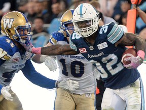 Toronto Argonauts running back James Wilder Jr. runs the ball and breaks a tackle against Winnipeg Blue Bombers linebacker Jovan Santos-Knox as linebacker Sam Hurl looks on during second half CFL football action in Toronto on Saturday, Oct. 21, 2017. THE CANADIAN PRESS/Nathan Denette