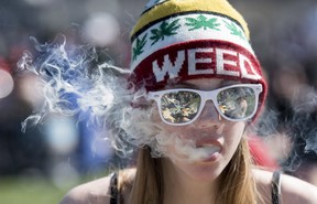 A woman exhales while smoking a joint during the annual 420 marijuana rally on Parliament hill on  April 20, 2016 in Ottawa.