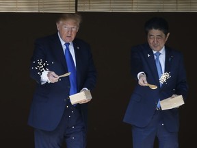 US President Donald Trump (L) and Japanese Prime Minister Shinzo Abe (R) feed koi fish during a welcoming ceremony in Tokyo on November 6, 2017.