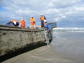 This handout picture taken on November 27, 2017 by the Oga city municipal office and released via Jiji Press shows coast guard officers inspecting a battered wooden boat where eight bodies were found inside at a beach in Oga, Japan's Akita prefecture. Japanese coastguard officials spotted eight bodies inside a battered wooden boat off northern Akita prefecture but waves had prevented officials from investigating since the boat was first spotted on November 24. Dozens of North Korean fishing vessels wash up on Japan's coast every year. Sometimes the boats' occupants have already died at sea, a phenomenon local media refer to as "ghost ships".  (AFP PHOTO / OGA CITY MUNICIPAL OFFICE / JIJI PRESS)