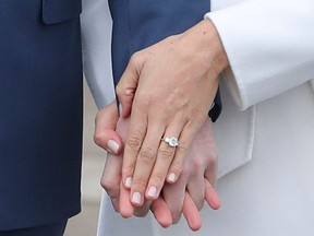 Britain's Prince Harry stands with his fiancée U.S. actress Meghan Markle as she shows off her engagement ring whilst they pose for a photograph in the Sunken Garden at Kensington Palace in west London on November 27, 2017. (DANIEL LEAL-OLIVAS/AFP/Getty Images)