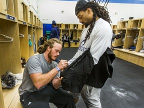 Toronto Argonauts' Bear Woods signs an article of clothing for Rico Murray as the team cleans out their lockers on Nov. 29, 2017
