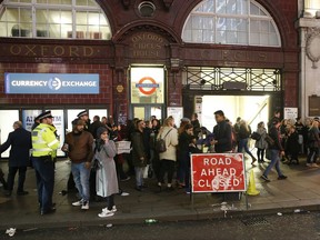 Police officers and members of the public walk near the entrance of Oxford Circus subway station in the west of London after it was reopened Friday Nov. 24, 2017.