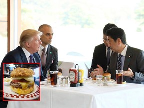 In this Nov. 5, 2017, file photo from the Prime Minister's Office Facebook page, U.S. President Donald Trump, left, listens to Japanese Prime Minister Shinzo Abe, right, during a lunch of hamburgers from Munch's Burger Shack at Kasumigaseki Country Club in Kawagoe, Japan. The cheeseburger Trump had is still drawing lines to the Tokyo burger joint. (Cabinet Public Relations Office of Japan via AP) and A 100 percent U.S. Angus beef Colby Jack Cheeseburger as part of U.S. President Donald Trump set is seen at Munch's Burger Shack restaurant in Tokyo Thursday, Nov. 16, 2017. The cheeseburger Trump had during his recent visit to Japan is still drawing lines at the Tokyo burger joint. (AP Photo/Eugene Hoshiko)