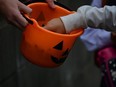 Cropped Image Of Hands Picking Candy From Halloween Basket