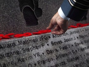 Military member puts a poppy on the ledge of B.C. Afghanistan Memorial, an 18,000 pound slab of granite honouring Canadian soldiers and civilians who served in Afghanistan is unveiled during a dedication ceremony in Victoria, B.C., on Saturday, September 30, 2017. THE CANADIAN PRESS/Chad Hipolito