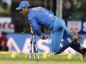 India's wicketkeeper Mahendra Singh Dhoni breaks the stumps to dismiss New Zealand's Tom Bruce during their third Twenty20 international cricket match in India, on Tuesday. (The Associated Press)