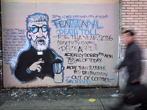 A man walks past a mural by street artist Smokey D. painted as a response to the fentanyl and opioid overdose crisis, in the Downtown Eastside of Vancouver on Dec. 22, 2016. (Darryl Dyck/The Canadian Press/Files)