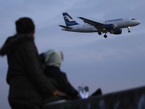 A woman and her two children watch a Finnair passenger plane arrive at Tegel Airport on October 17, 2011 in Berlin, Germany.  (Photo by Sean Gallup/Getty Images)