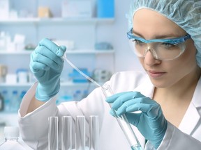 In this stock photo, a young female scientist loads a liquid sample into test tube.