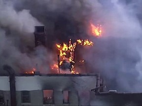 In this image taken from video provided by WABC, firefighters battle a large fire on the top floor of an apartment building in the Harlem neighborhood of New York.