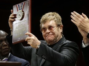 Elton John holds up the 2017 Harvard Humanitarian of the Year Award after being presented with it Monday, Nov. 6, 2017, during ceremonies at Harvard University, in Cambridge, Mass.