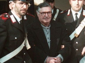 In this Jan. 16, 1996 file photo, Mafia ''boss of bosses'' Salvatore ''Toto'' Riina, center, enters handcuffed into Bologna's bunker-courtroom, escorted by Carabinieri, Italian paramiliary police, in Bologna, Italy.