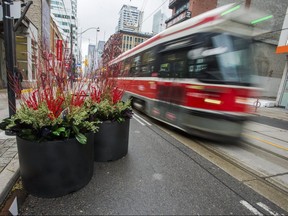 A TTC streetcar passes planters along King St. W. as it heads westbound towards Spadina Ave. during the first work day of King Street Pilot Project in Toronto on Monday, Nov. 13, 2017.