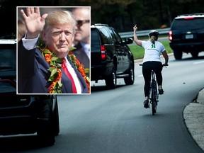 A woman on a bike gestures with her middle finger as a motorcade with US President Donald Trump departs Trump National Golf Course October 28, 2017 in Sterling, Virginia. / AFP PHOTO / Brendan SmialowskiBRENDAN SMIALOWSKI/AFP/Getty Images