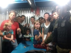 This Nov. 1, 2017 photo provided by Brazil's Secretary of State for Public Security and Social Defense, Adam Harteau, left, Emily Harteau, third from right, and their two daughters, are shown with military police officers and residents, in the Breves municipality, in the Brazil state of Para. The California couple along with their 3- and 7-year-old daughters who had been missing for days after pirates attacked their boat in the Amazon River delta area have been found alive. (Secretary of State for Public Security and Social Defense via AP)