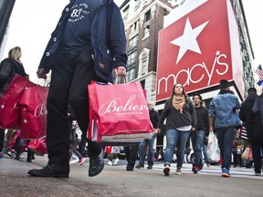 FILE - In this Nov. 27, 2015, file photo, shoppers carry bags as they cross a pedestrian walkway near Macy's in Herald Square, in New York. At Macy's flagship store in New York, a chance to sit on Santa Claus' lap is by appointment only in 2017, for the first time ever. (AP Photo/Bebeto Matthews, File)