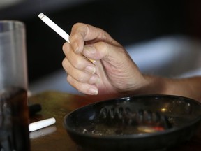 FILE - In this April 21, 2015, file photo, a patron smokes a cigarette inside a bar in New Orleans hours before a smoking ban takes effect in bars, gambling halls and many other public places such as hotels, workplaces, private clubs and stores. Cigarette smoking, over-eating and other unhealthy behaviors can be blamed for nearly half of U.S. cancer deaths each year, according to a new American Cancer Society study released Tuesday, Nov. 21, 2017. (AP Photo/Gerald Herbert, File)