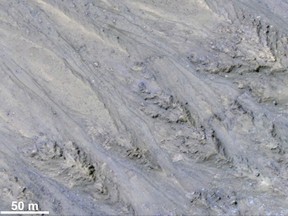 This image provided by NASA shows the inner slope of a Martian crater which has several of the seasonal dark streaks called "recurrent slope lineae," or RSL, that a November 2017 report interprets as granular flows, rather than darkening due to flowing water. Arizona scientists said Monday, Nov. 20, 2017 that these lines appear more like dry, steep flows of sand, rather than water trickling downhill, at or near the surface. (NASA via AP)