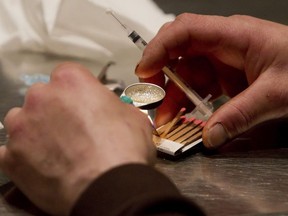 In this Wednesday, May 11, 2011, file photo, a man prepares heroin he bought on the street to be injected at the Insite safe injection clinic in Vancouver, British Columbia.