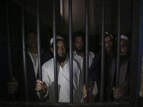 Relatives of a newlywed couple stand behind bars at a police station in Karachi, Pakistan, Monday, Nov. 27, 2019.