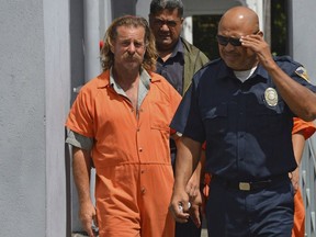 In this Oct. 4, 2016, file photo provided by the Samoa News, Dean Jay Fletcher, left, is escorted by a police officer after his initial appearance in the District Court of American Samoa in Pago Pago, American Samoa. A U.S. judge in Hawaii has ordered the release of U.S. citizen Fletcher, being held for extradition to Tonga, where he's accused of beating his wife to death, escaping police and sailing some 300 miles to American Samoa. (Ausage Fausia/SamoaNews via AP, File)