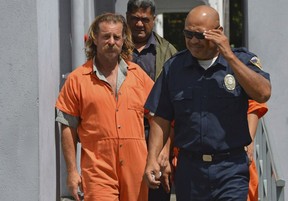 In this Oct. 4, 2016, file photo provided by the Samoa News, Dean Jay Fletcher, left, is escorted by a police officer after his initial appearance in the District Court of American Samoa in Pago Pago, American Samoa. A U.S. judge in Hawaii has ordered the release of U.S. citizen Fletcher, being held for extradition to Tonga, where he's accused of beating his wife to death, escaping police and sailing some 300 miles to American Samoa. (Ausage Fausia/SamoaNews via AP, File)