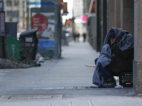 A homeless man peers outs from his blankets at the corner of  Richmond St. W  and Bay St. above heated grates as the arctic-like blast in Toronto continued on Sunday February 15, 2015 Environment Canada reported the weather as -25C with a windchill of -40C.