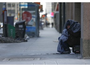 A homeless man peers outs from his blankets at the corner of  Richmond St. W  and Bay St. above heated grates as the arctic-like blast in Toronto continued on Sunday February 15, 2015 Environment Canada reported the weather as -25C with a windchill of -40C.