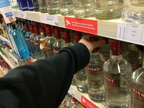 A customer grabs a bottle of vodka from a liquor store shelf