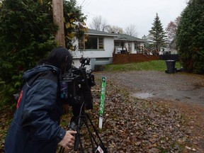 A journalist films a house in Sainte-Marthe-Sur-Le-Lac, Que., Thursday, Nov.2, 2017. Quebec provincial police say a woman is facing three counts of first-degree murder in the deaths of three newborns.
