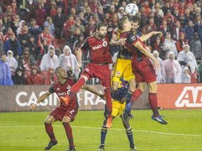 Toronto FC's Nick Hagglund, right, and teammate Drew Moor, centre left, clear the ball from New York Red Bulls' Damien Perrinelle, centre right, during second half MLS Eastern Conference semifinal action in Toronto on Sunday, November 5, 2017. THE CANADIAN PRESS/Chris Young