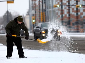 Chris Elliot from Local Lous on 16 Ave. shovels snow as Calgarians woke up to a blast of winter with more snow in the forecast on Thursday November 2, 2017.