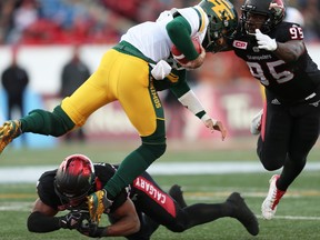 Edmonton Eskimos Mike Reilly is tackled by Jameer Thurman and Ja'Gared Davis of the Calgary Stampeders during the 2017 CFL Western Final in Calgary on Sunday. (Al Charest/Postmedia)