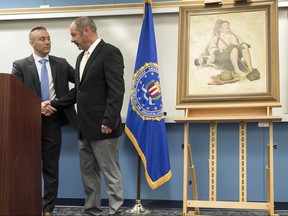 In this March 31, 2017, file photo, John Grant, right, shakes hands with FBI Special Agent Jacob Archer, left, after taking custody of a recovered Norman Rockwell painting stolen during a 1976 break-in at the Grant family's home in Cherry Hill, N.J.