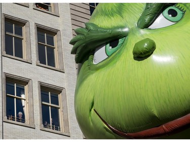 The Grinch balloon passes by windows of a building on Central Park West during Macy's Thanksgiving Day Parade in New York Thursday, Nov. 23, 2017. (AP Photo/Craig Ruttle)