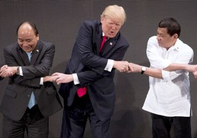 U.S. President Donald Trump, center, reacts as he does the "ASEAN-way handshake" with Vietnamese President Tran Dai Quang, left, and Philippines President Rodrigo Duterte on stage during the opening ceremony at the ASEAN Summit at the Cultural Center of the Philippines, Monday, Nov. 13, 2017, in Manila, Philippines. Trump initially did the handshake incorrectly. Trump is on a five-country trip through Asia traveling to Japan, South Korea, China, Vietnam and the Philippines. (AP Photo/Andrew Harnik)