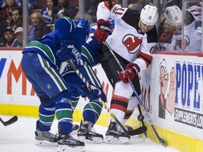 New Jersey Devils' Brian Boyle (11) battles Vancouver Canucks' Michael Del Zotto, left, and Erik Gudbranson, back, for the puck during the first period of an NHL hockey game in Vancouver, B.C., on Wednesday November 1, 2017. THE CANADIAN PRESS/Darryl Dyck