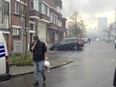 A man covers his face from smoke as he walks near the burning Milcamps waffle factory in Brussels, Thursday, Nov. 23, 2017.