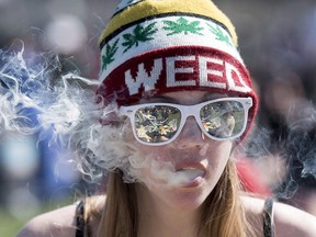 A woman exhales while smoking a joint during the annual 420 marijuana rally on Parliament hill on Wednesday, April 20, 2016 in Ottawa. THE CANADIAN PRESS/Justin
