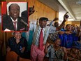 Members of Zimbabwe's association of war veterans sing old songs from the war of independence at a press conference held by their leader Chris Mutsvangwa, in which he called for President Robert Mugabe (inset) to step down, in downtown Harare, Zimbabwe Tuesday, Nov. 21, 2017. (AP Photos)