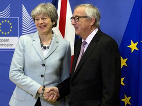 British Prime Minister Theresa May, left, is greeted by European Commission President Jean-Claude Juncker, right, prior to a meeting at EU headquarters in Brussels on Friday, Dec. 8, 2017.
