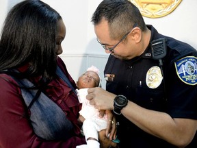 Savannah-Chatham police officer William Eng, right, plays with 29-day-old Bella Adkins while her mother, Tina Adkins, holds her on Monday, Dec. 4, 2017, at Savannah-Chatham police headquarters.