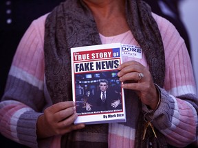 In a Nov. 17, 2017 file photo, a supporter holds up a Fake News book while Kayla Moore, wife of U.S. Senate candidate Roy Moore, speaks at a press conference in Montgomery, Ala.